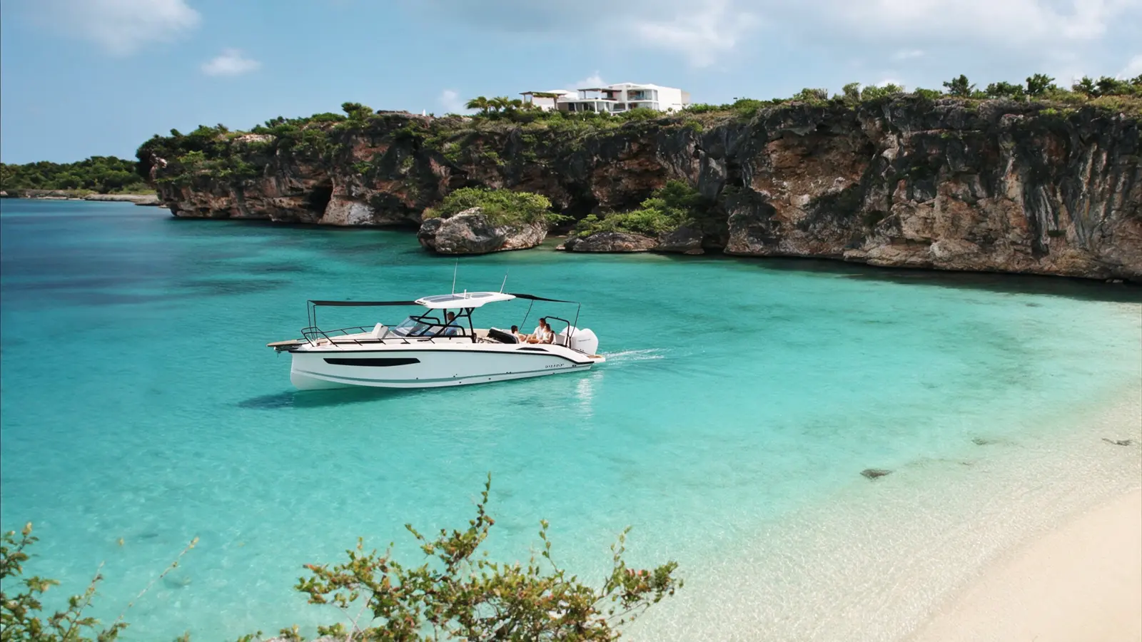 Modern boat beneath the dramatic Caribbean coastline